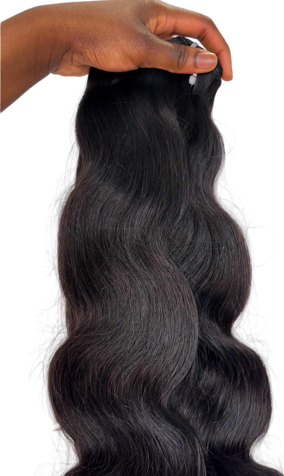 Black hair extensions held by a hand on a white background